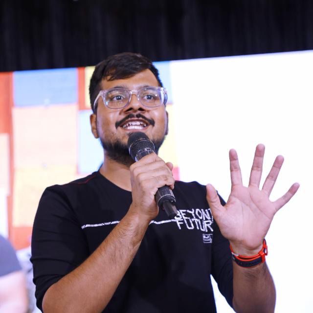 Darsh Chandura speaking on stage with microphone